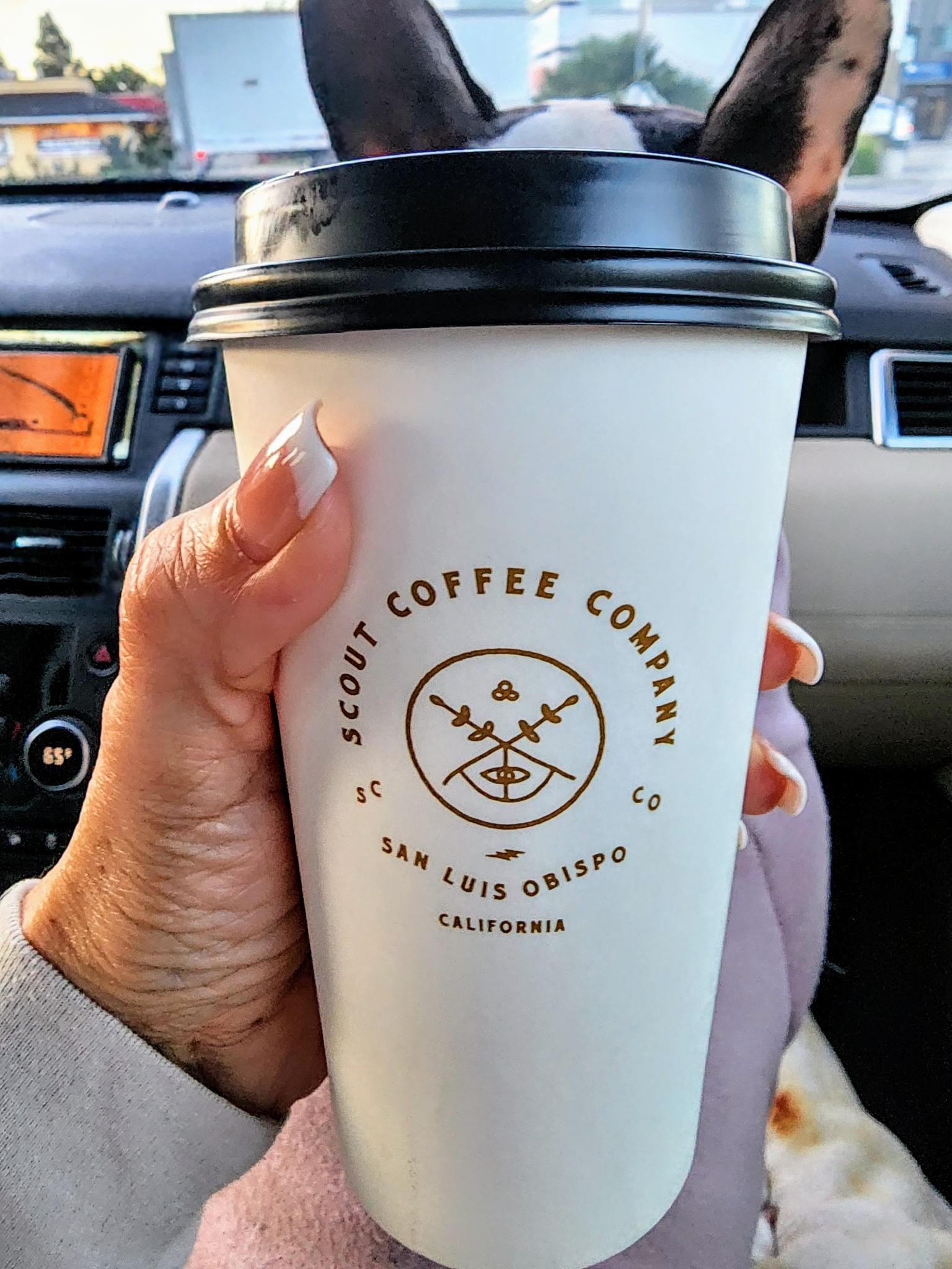 Andie holding a Scout Coffee cup on a coast trip