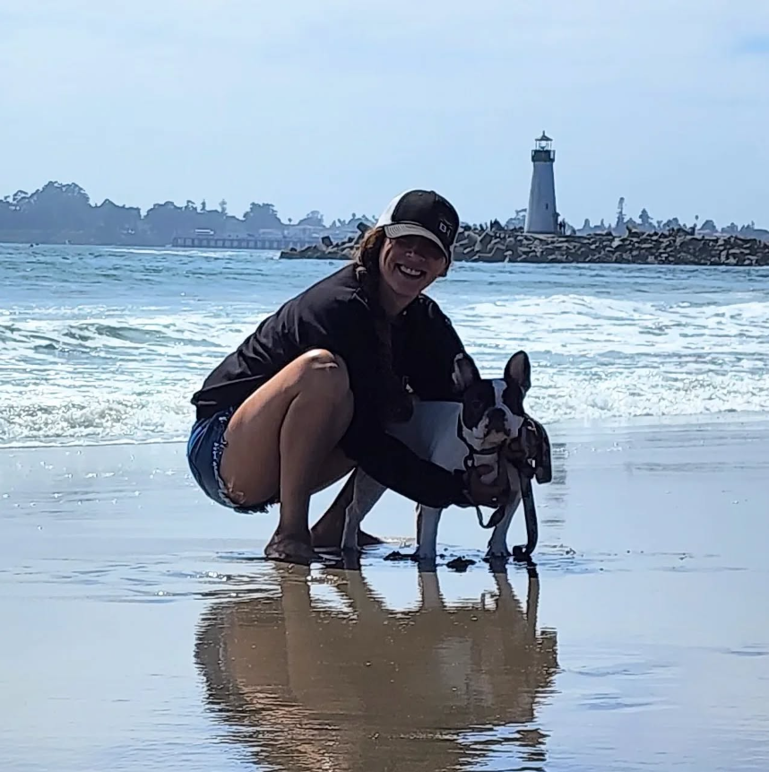 Andie and Piper together at the ocean, with a lighthouse beyond the water
