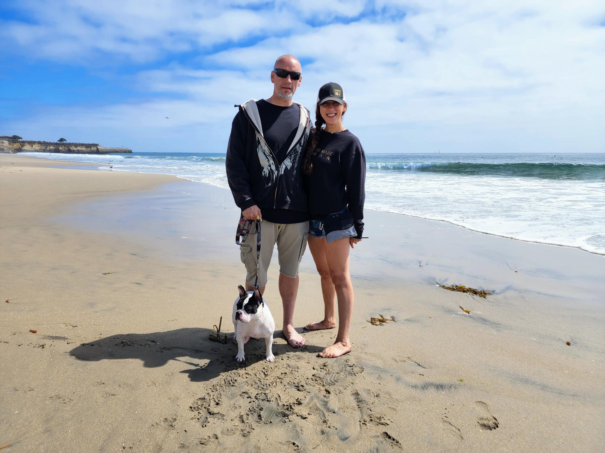 Andie and Greg standing with Piper at the beach