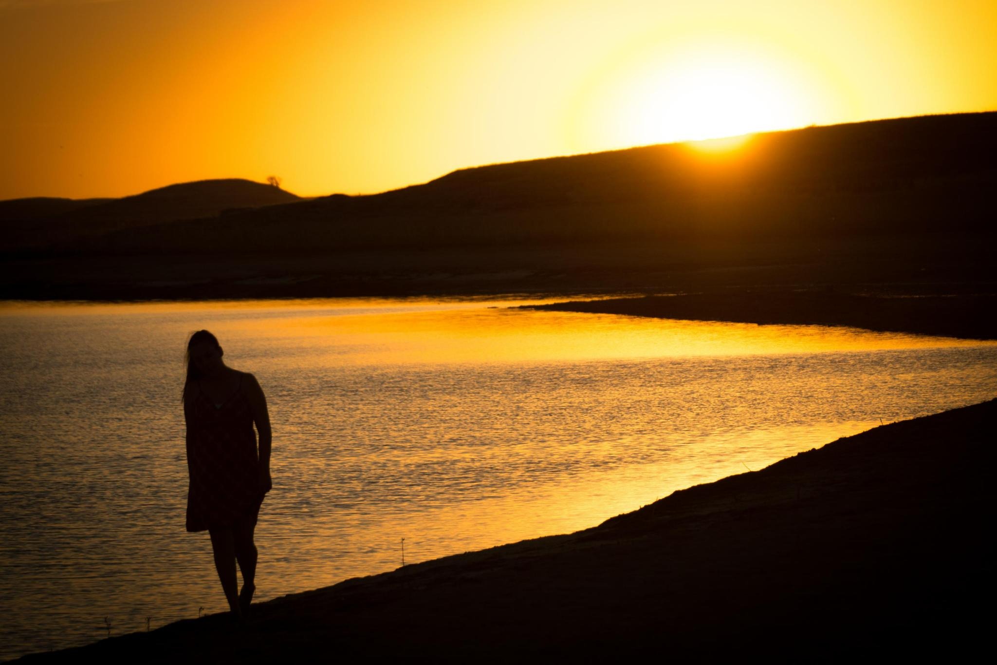 Andie silhouetted beside glowing water at sunset