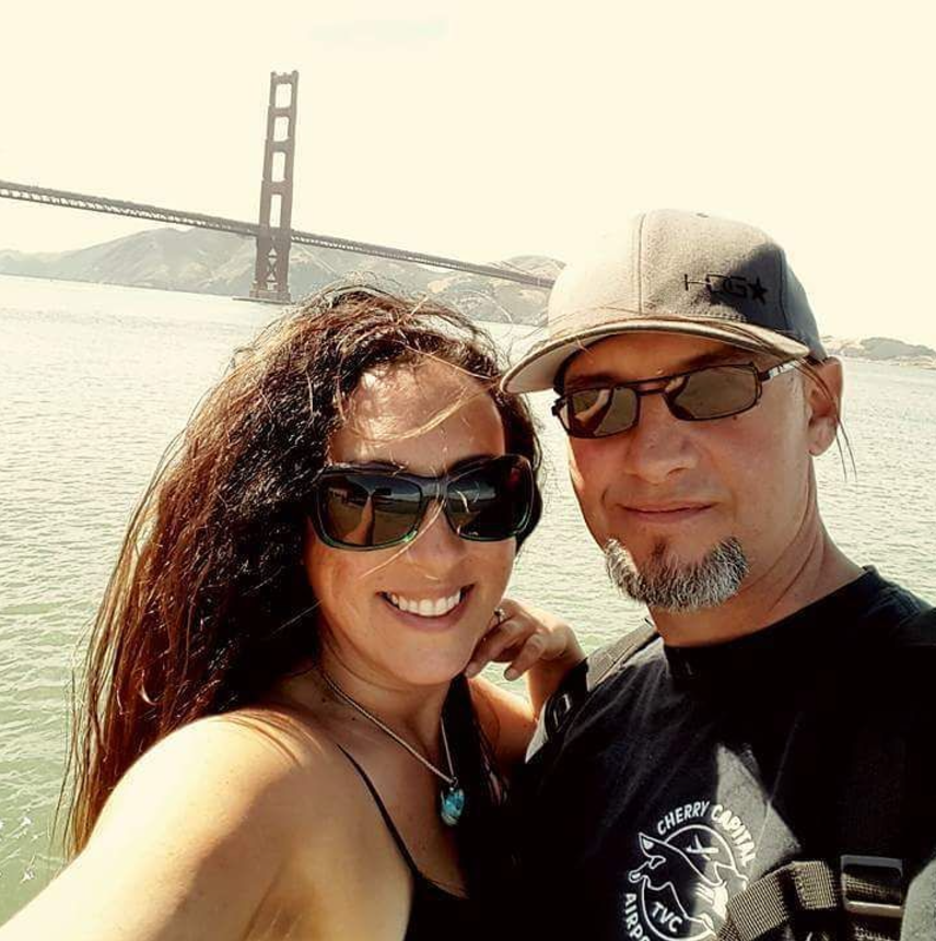 Andie and Greg smiling beside the Golden Gate Bridge